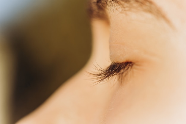 Closed eye of a young boy close up. Cropped portrait of a Caucasian man in the sun.