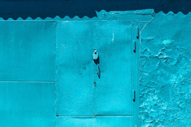 Closed imperfect blue garage gate with padlock close-up