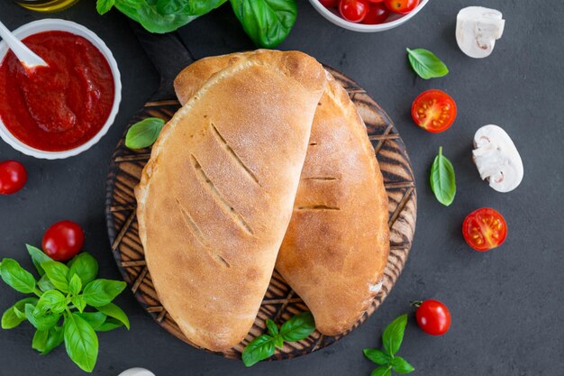 closed Italian calzone pizza with tomato sauce mozzarella cheese and mushrooms on a board