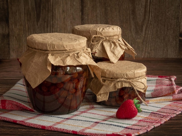 Closed jars of jam on a kitchen towel and fresh berries preserved for the winter