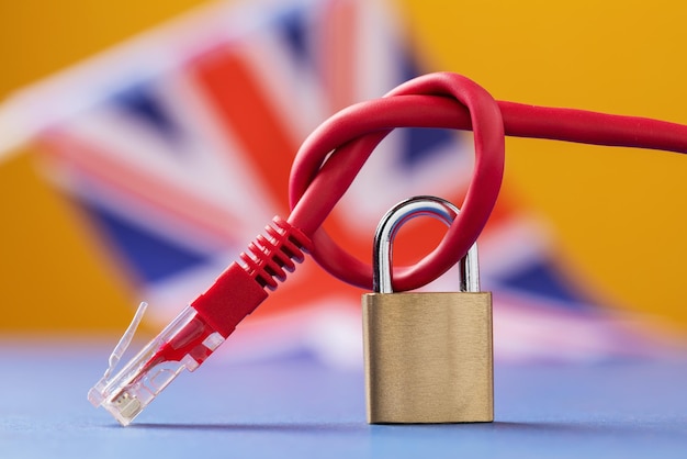 A closed lock on a tied network wire against the background of the British flag a concept