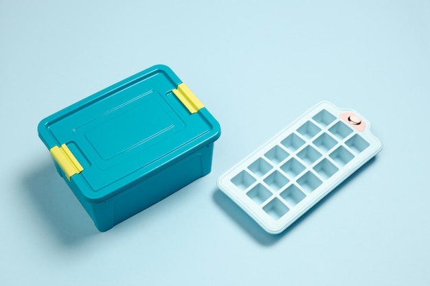 Closed lunch box, ice form. Monochrome stylish and trendy composition in blue color on studio wall. Top view, flat lay.