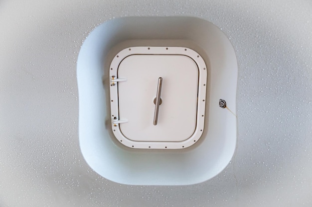 Closed marine watertight iron door on a white ship hull closeup