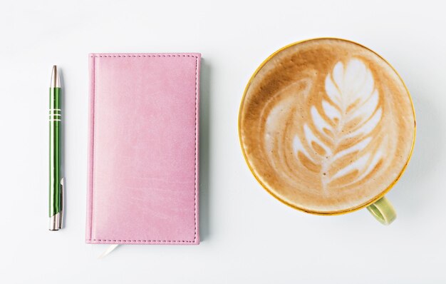 Closed notebook with pen and coffee flat lay