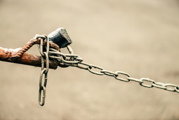 Photo closed padlock on chain of brown fence is close-up on background of asphalt with bokeh with copy space