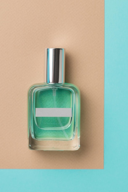 A closed perfume bottle on a blue and beige background. Flat lay.