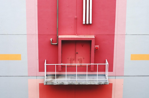 Photo closed red door and balcony of building