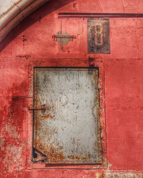 Closed rusty door on red wall