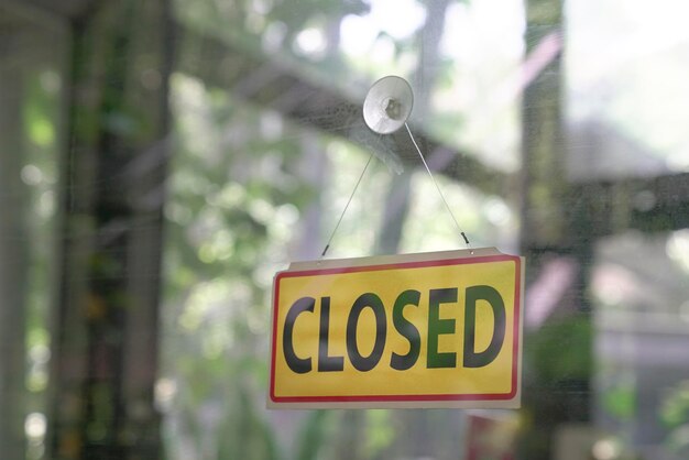 Closed signboard hanging on glass door of a restaurant