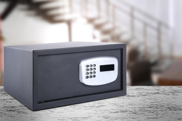 Closed steel safe with electronic lock on light grey table indoors