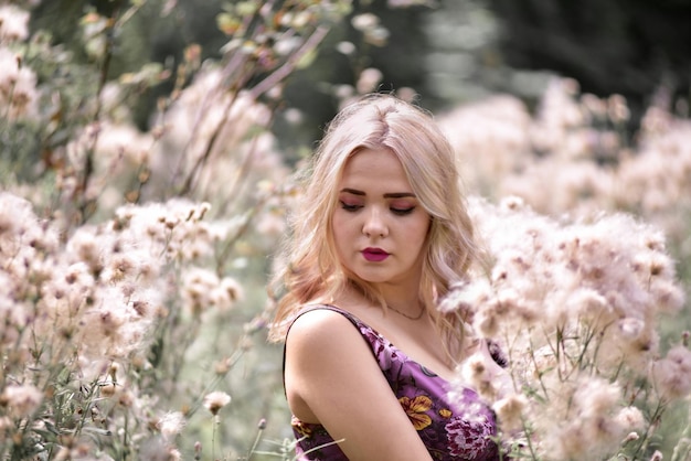 Photo closed-up of beautiful young woman with blond hair standing amidst flowers