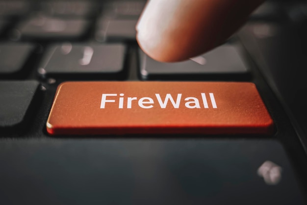 Closed up finger on keyboard with word firewall