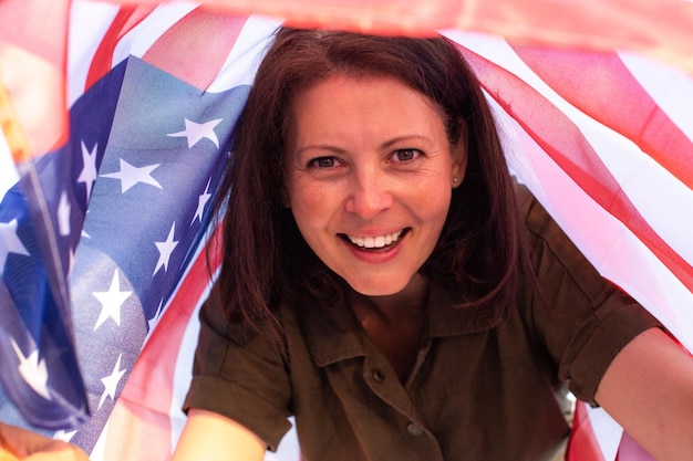 Closed up portrait of mature happy beautiful woman holding USA flag