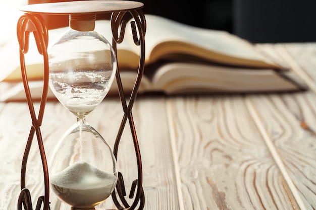 Photo closed up of sandglass or hourglass on background of book