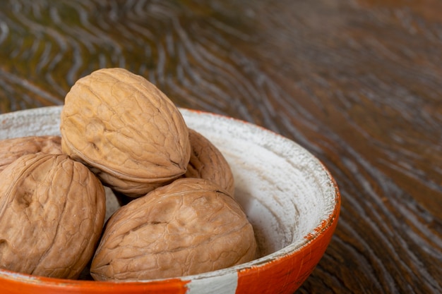 Closed walnuts in the pot and rustic wooden background. selective focus.