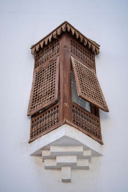 Closed window with wooden bars in an old white wall of a house on the street of Egypt in Sharm El Sheikh