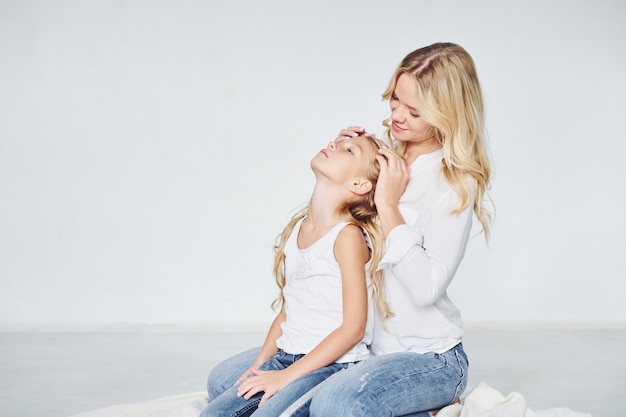 Closeness of the people. Mother with her daughter together in the studio with white background.