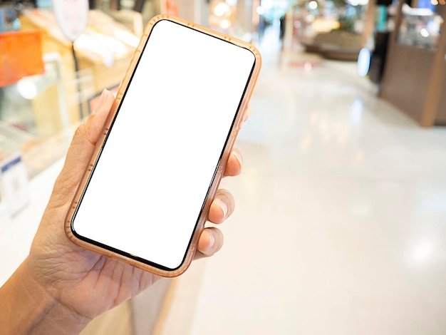 Closesup hand holding mobile screen smartphone with supermarket blurred background