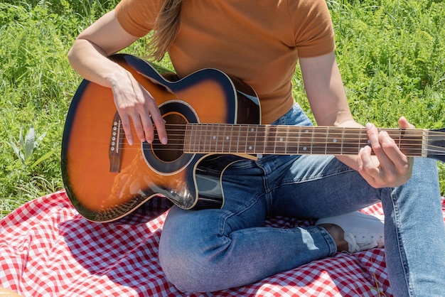 Closeuo of young woman playing guitar on a picnic