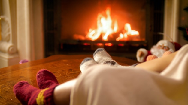 Крупный план 4k кадры семьи, лежащей под одеялом в теплых шерстяных носках, греющихся у огня в камине. люди отдыхают на зимних праздниках и праздниках дома
