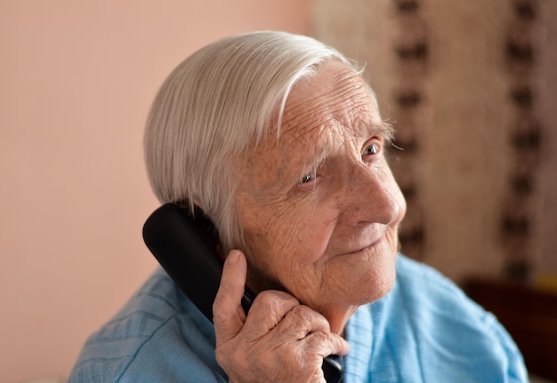 Closeup of a 90yearold elderly retired woman who is talking smiling on the phone