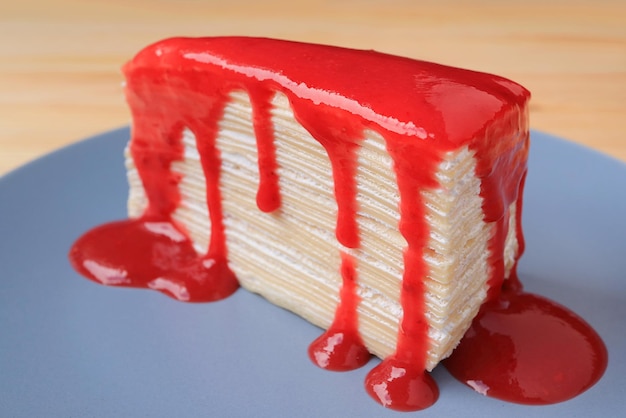 写真 ラズベリーソースとおいしそうなバニラミルクレープケーキのスライスをクローズアップ