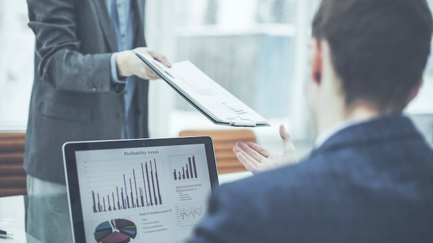 Closeup of the accountant, passes into the hands of the Manager Finance financial report for the workplace in the office