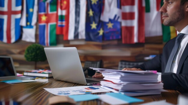 Photo a closeup of an administrative leader sitting at their desk with a stack of papers and a laptop open