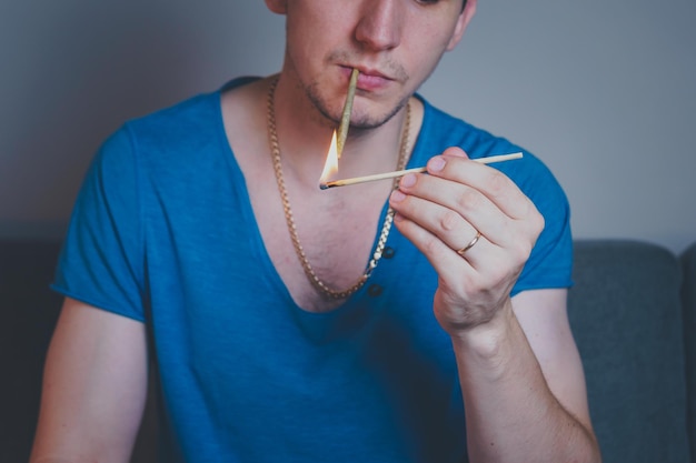 Closeup of adult man lights up with matches and smoking medical marijuana joint