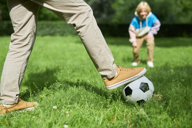 公園のコピースペースで緑の芝生などでサッカーをする成人男性のクローズアップ