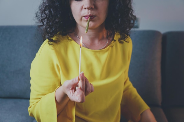 Closeup of adult woman lights up with matches and smoking medical marijuana joint