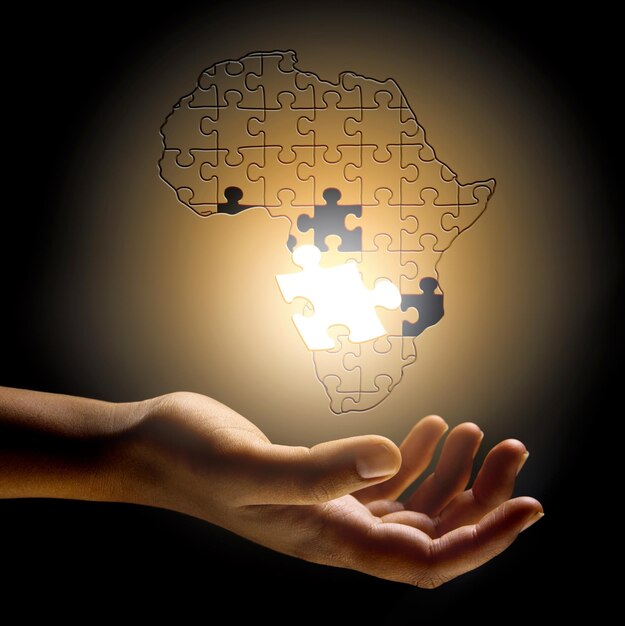 Foto primo piano africa e mano con uno sviluppo di puzzle e risoluzione dei problemi per la crescita futura e la pianificazione ingrandisci le dita o la persona con il simbolo solidarietà e supporto per l'innovazione e la soluzione globale