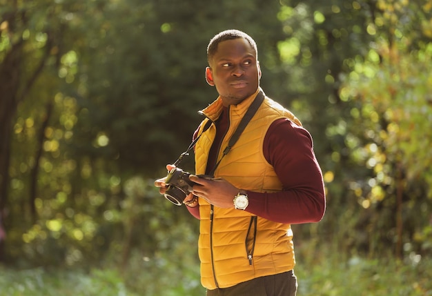 Photo closeup african american guy photographer taking picture with photo camera on city green park leisure activity diversity and hobby concept