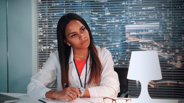 Closeup of african american psychologist attentively listening to patients story and writing notes i...