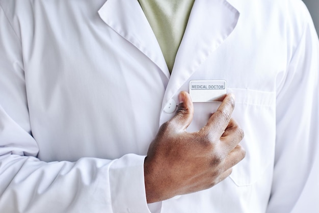 Closeup of african male doctor attaching badge on his white coat