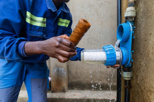 Closeup of African plumber showing one dirty and one clean filters Changing water filters