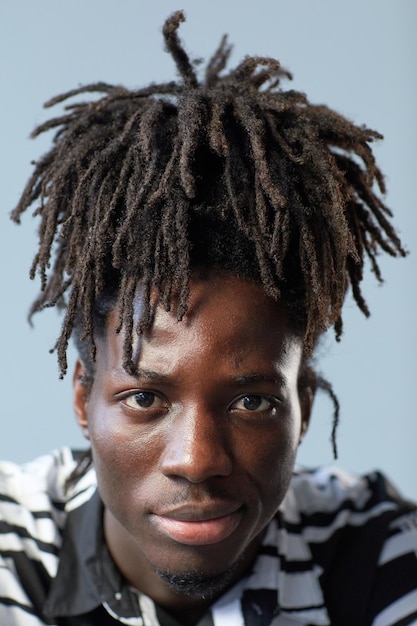 Closeup of african young guy with stylish hairstyle looking at camera on blue background