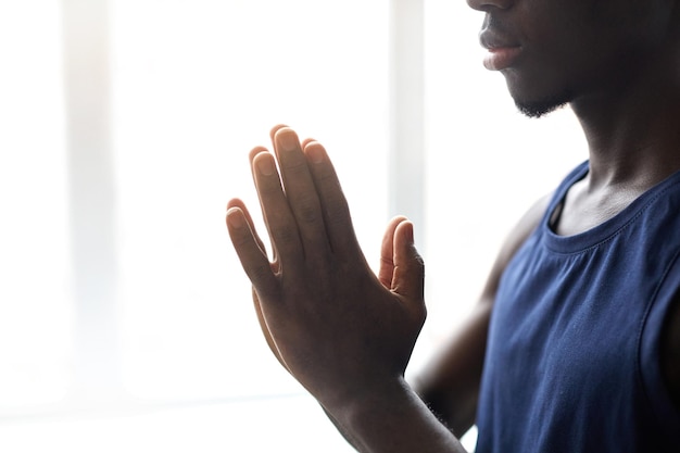 Closeup of african young man folding his hands and concentrating on meditation during yoga practice