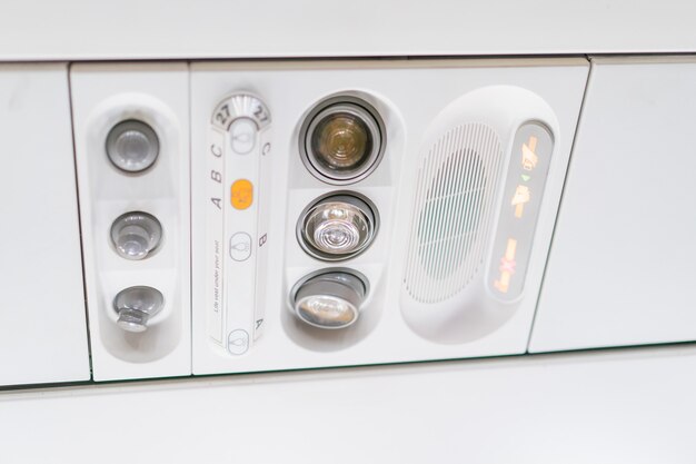 Closeup airplane Console panel; lamp, light, need help button, air condition, sefty belt and no smoking lighting sign.