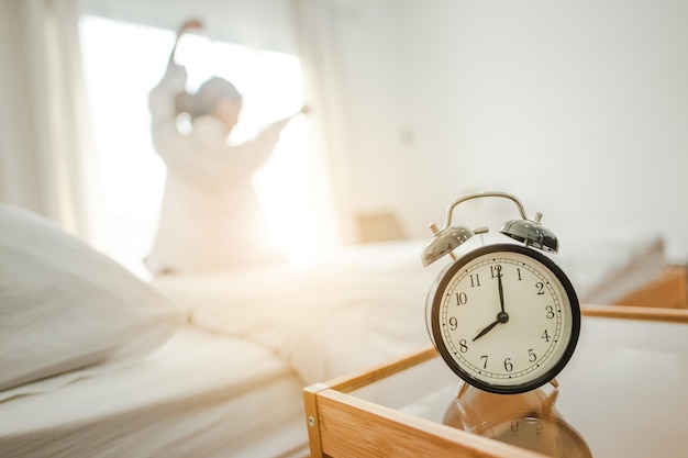 Photo closeup alarm clock in bed after waking up sunlight in morning