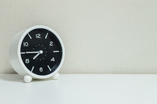 Closeup alarm clock for decorate in a quarter to eight on wood desk