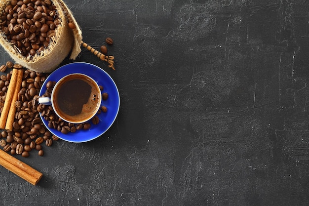 Близкий и верхний вид горячего черного кофе в голубой чашке кофе и обжаренных тайских кофейных бобов на деревянной