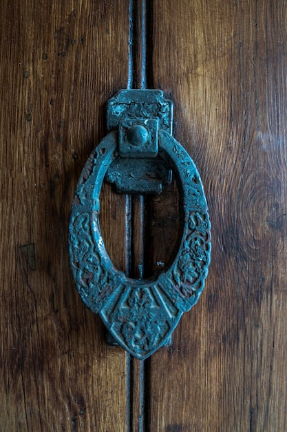 Closeup of an antique old metal door handle on the wooden door