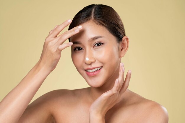 Photo closeup ardent girl with soft makeup applying moisturizing cream on her nose