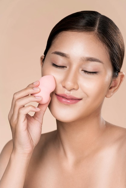 Closeup ardent woman applying her cheek with dry powder while looking at camera