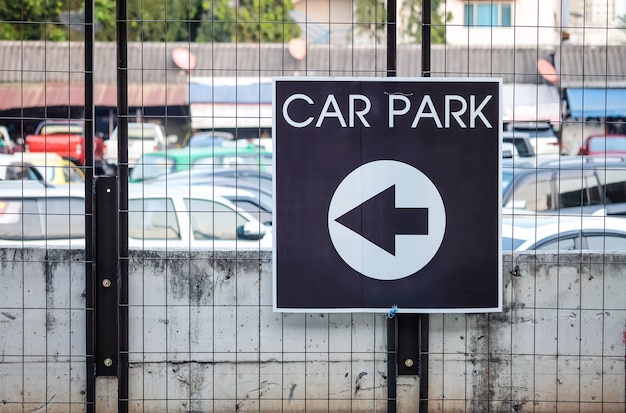 Closeup arrow signs tell the way to car park on iron fence textured background