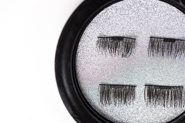 Photo closeup of artificial eyelashes on a magnet on a silver background