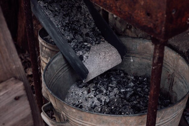 Closeup of ashes from wood put in iron bucket under old brazier used for fertilizing soil Ecofriendly and organic fertilization People thinking about future