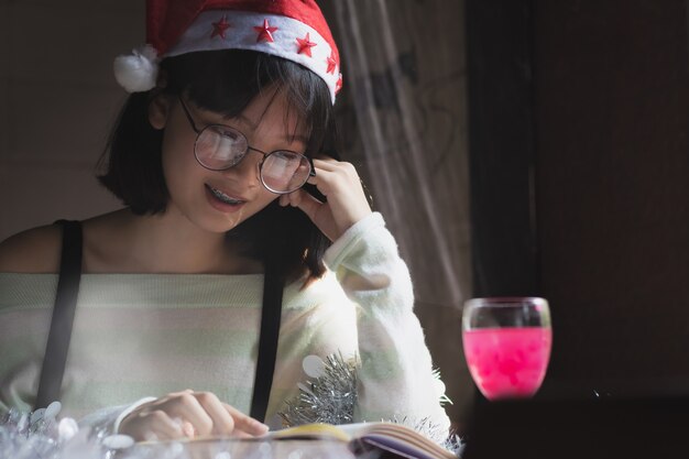  closeup Asia woman, teen girl wear Christmas hat reading book with happy.