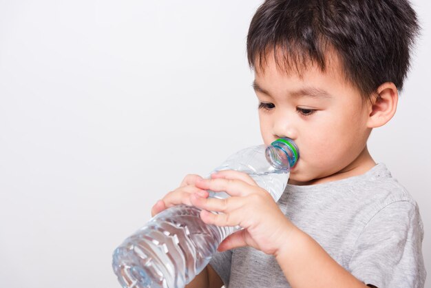 クローズアップアジアの顔ペットボトルから水を飲む小さな子供の男の子